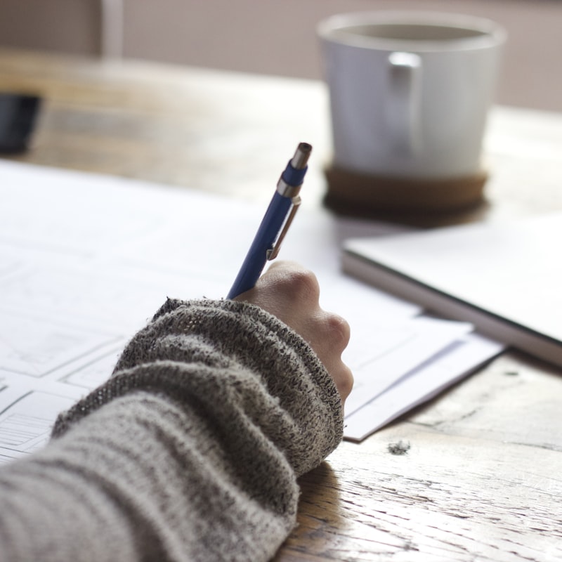 Manos escribiendo y corrigiendo un texto sobre un escritorio